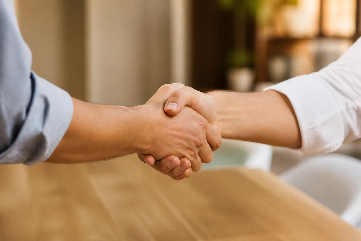Poignée de main cadrée sur les mains au-dessus d&rsquo;un bureau clair